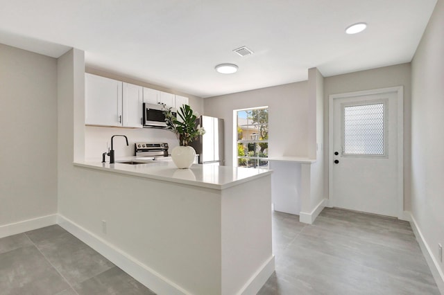 kitchen featuring appliances with stainless steel finishes, a sink, light countertops, and baseboards