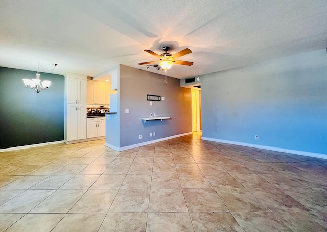 unfurnished living room with a chandelier, ceiling fan, light tile patterned floors, and baseboards