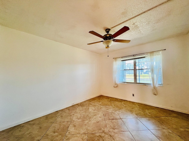 empty room featuring a ceiling fan, light tile patterned flooring, and baseboards