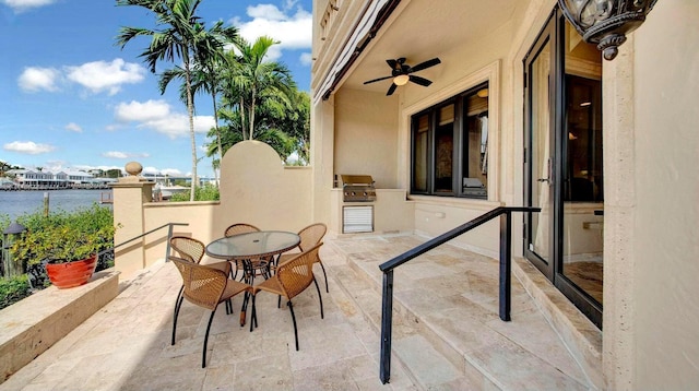 view of patio featuring exterior kitchen, a water view, outdoor dining space, and a grill