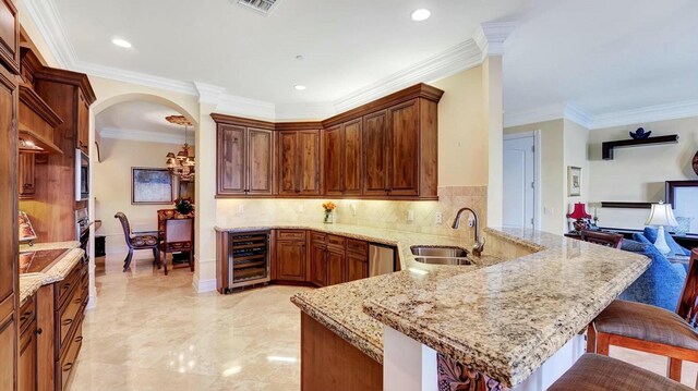 kitchen featuring beverage cooler, a sink, a peninsula, ornamental molding, and a kitchen bar