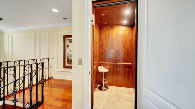 hall with elevator, crown molding, and an upstairs landing