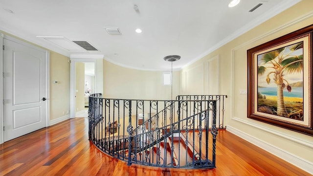 corridor with an upstairs landing, wood finished floors, baseboards, and ornamental molding