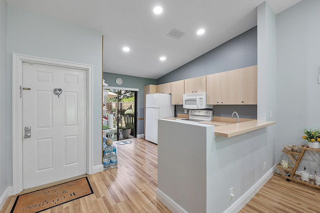 3839 Coco Loba Ln, Boynton Beach, FL 33436 - kitchen featuring white appliances, a peninsula, light brown cabinetry, baseboards, and vaulted ceiling
