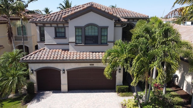 mediterranean / spanish-style home featuring a tiled roof and decorative driveway