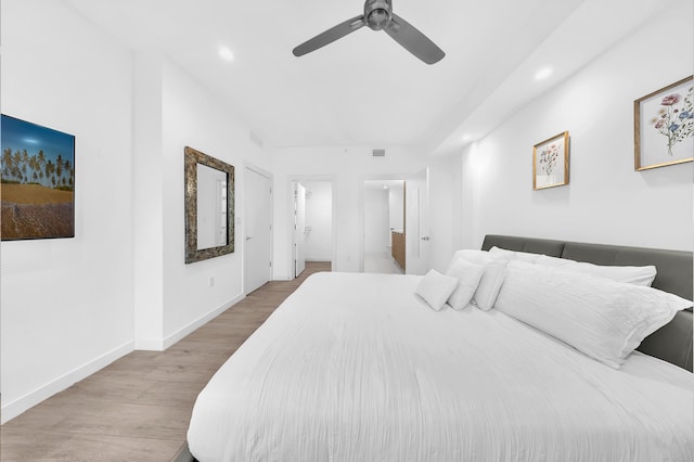 bedroom with wood finished floors, recessed lighting, baseboards, ceiling fan, and ensuite bath