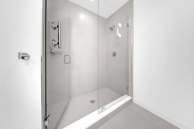bathroom with a shower stall, baseboards, and tile patterned flooring