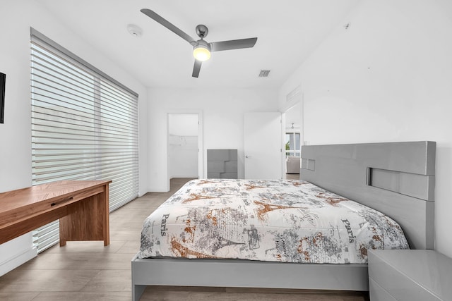 bedroom featuring a spacious closet, a closet, a ceiling fan, and wood finished floors