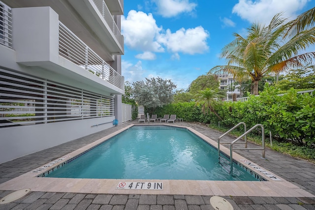 view of swimming pool with a patio and fence