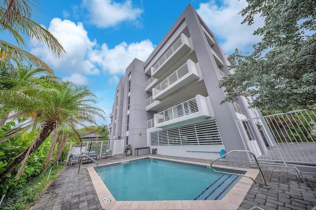 community pool with fence and a patio area