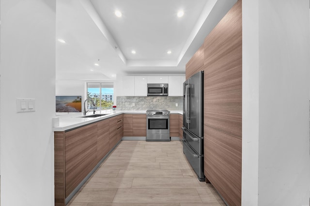 kitchen featuring stainless steel appliances, modern cabinets, white cabinetry, light countertops, and backsplash