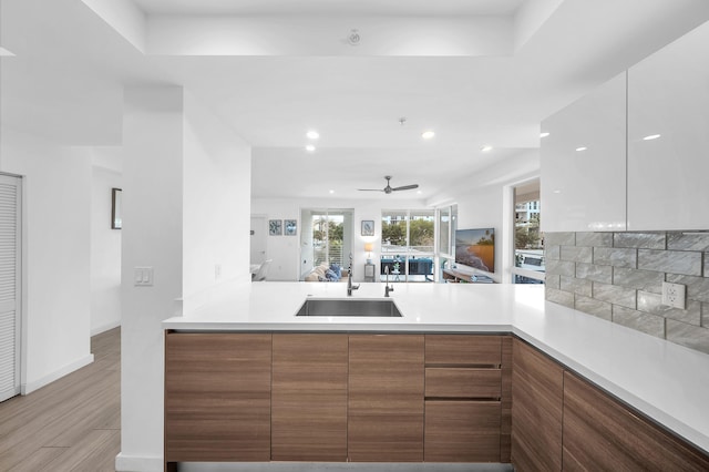 kitchen with a sink, modern cabinets, light countertops, and recessed lighting