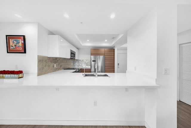 kitchen featuring appliances with stainless steel finishes, a sink, a peninsula, light countertops, and recessed lighting