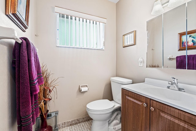 half bath featuring tile patterned floors, toilet, vanity, and baseboards