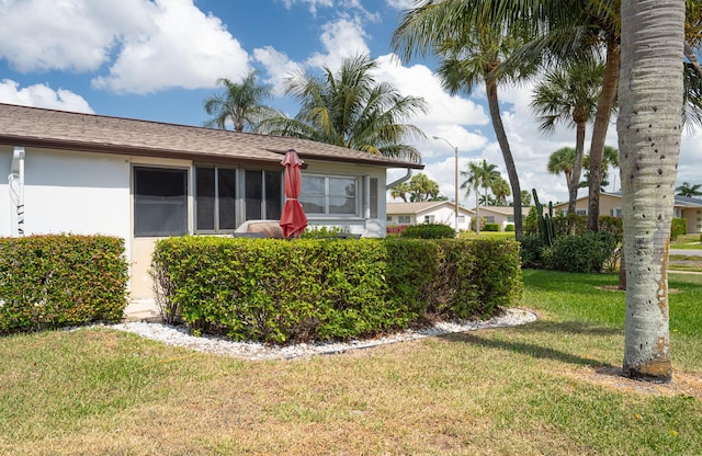 view of side of property with stucco siding and a yard