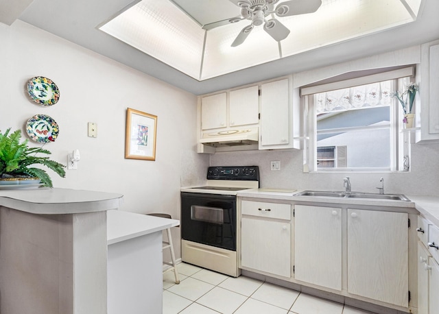 kitchen with range with electric cooktop, a sink, under cabinet range hood, light countertops, and light tile patterned floors
