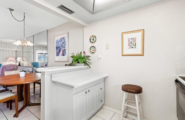 kitchen featuring light tile patterned floors, a chandelier, a peninsula, light countertops, and white cabinetry