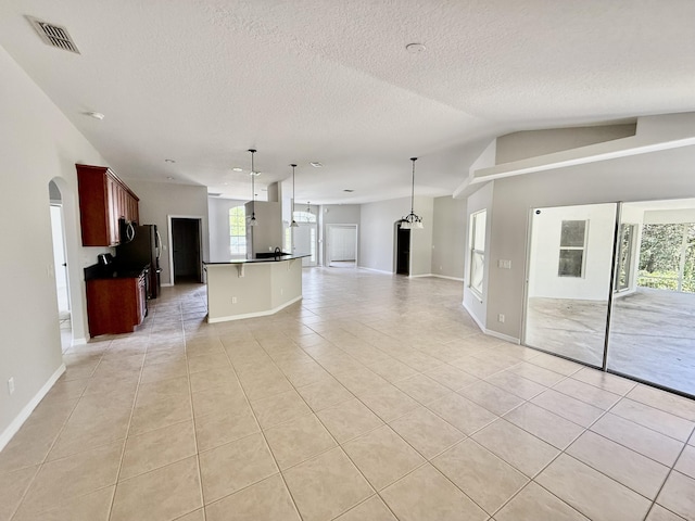 1744 SW Nantucket Ave, Port Saint Lucie, FL 34953 - unfurnished living room featuring light tile patterned floors, baseboards, vaulted ceiling, a textured ceiling, and arched walkways