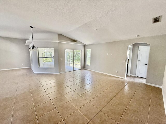1744 SW Nantucket Ave, Port Saint Lucie, FL 34953 - unfurnished room with light tile patterned flooring, vaulted ceiling, arched walkways, baseboards, and a textured ceiling