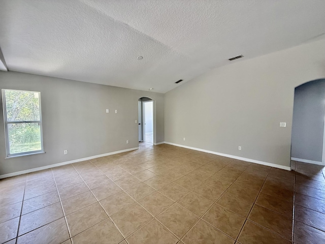 1744 SW Nantucket Ave, Port Saint Lucie, FL 34953 - empty room featuring arched walkways, light tile patterned floors, a textured ceiling, and baseboards
