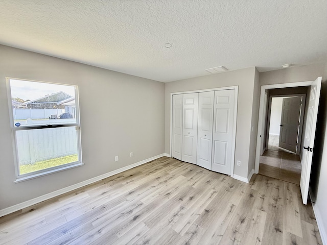 1744 SW Nantucket Ave, Port Saint Lucie, FL 34953 - unfurnished bedroom with light wood-type flooring, baseboards, a textured ceiling, and a closet