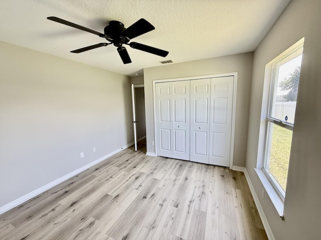 1744 SW Nantucket Ave, Port Saint Lucie, FL 34953 - unfurnished bedroom featuring multiple windows, light wood-style floors, a closet, baseboards, and a textured ceiling