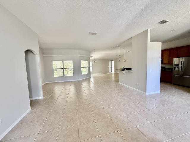 1744 SW Nantucket Ave, Port Saint Lucie, FL 34953 - unfurnished living room with light tile patterned floors, a textured ceiling, baseboards, and arched walkways