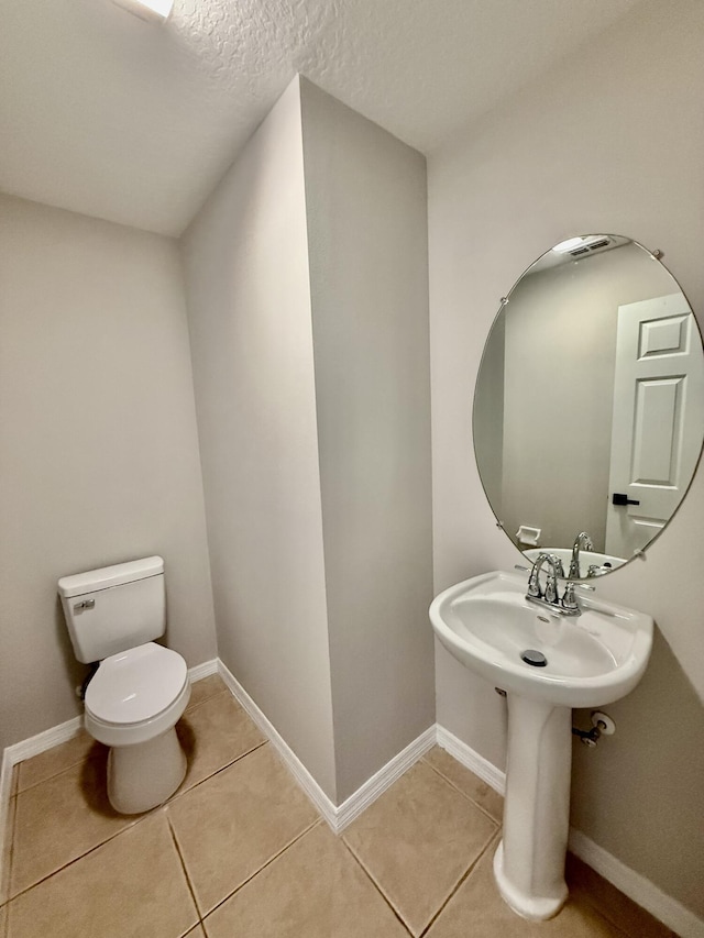 1744 SW Nantucket Ave, Port Saint Lucie, FL 34953 - half bathroom featuring toilet, tile patterned flooring, baseboards, and a textured ceiling