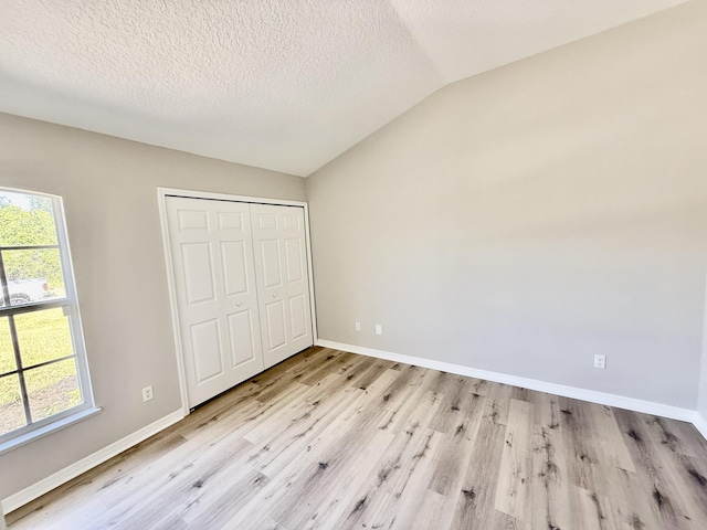 1744 SW Nantucket Ave, Port Saint Lucie, FL 34953 - unfurnished bedroom with lofted ceiling, light wood-type flooring, multiple windows, baseboards, and a textured ceiling