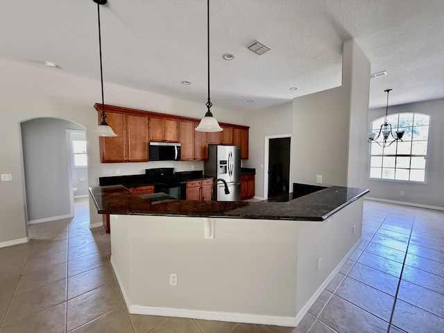 1744 SW Nantucket Ave, Port Saint Lucie, FL 34953 - kitchen with stainless steel appliances, arched walkways, baseboards, a textured ceiling, and light tile patterned flooring
