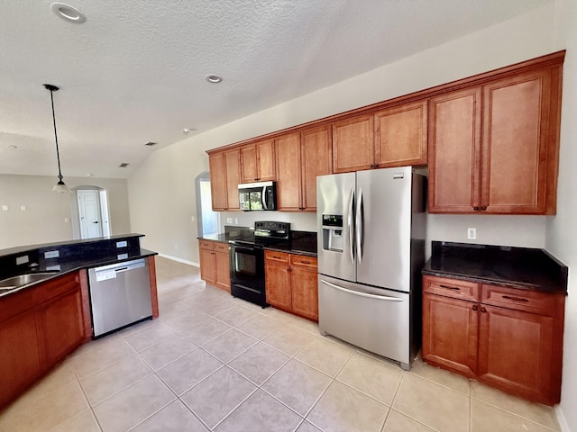 1744 SW Nantucket Ave, Port Saint Lucie, FL 34953 - kitchen with stainless steel appliances, arched walkways, brown cabinets, dark countertops, and a textured ceiling