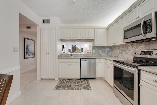 6698 10th Ave N Unit 320, Lake Worth, FL 33467 - kitchen with appliances with stainless steel finishes, decorative backsplash, a sink, a textured ceiling, and baseboards