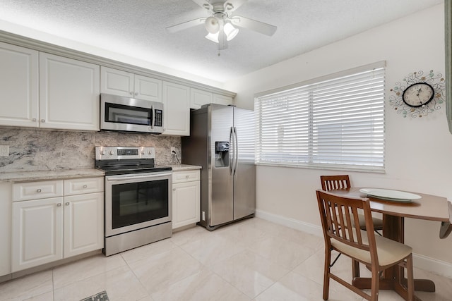6698 10th Ave N Unit 320, Lake Worth, FL 33467 - kitchen featuring appliances with stainless steel finishes, baseboards, decorative backsplash, a textured ceiling, and ceiling fan