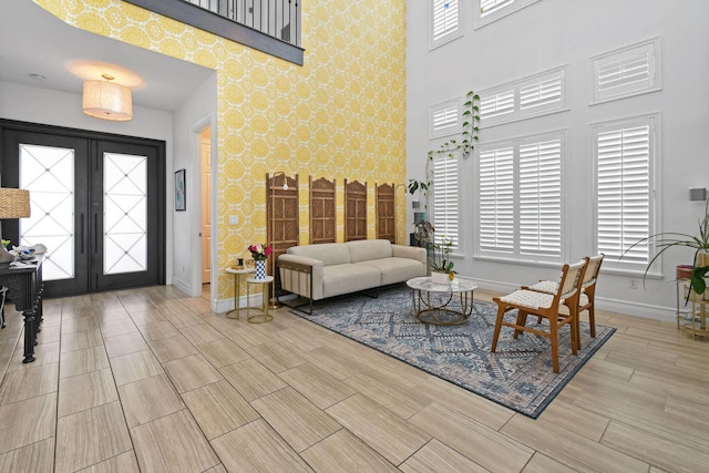 16323 Pantheon Pass, Delray Beach, FL 33446 - living room featuring baseboards, french doors, an accent wall, a towering ceiling, and wallpapered walls