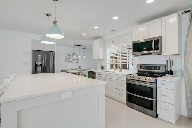 kitchen with stainless steel appliances, white cabinetry, recessed lighting, a kitchen island, and pendant lighting