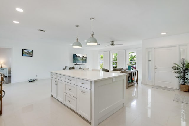 kitchen featuring recessed lighting, light tile patterned floors, decorative light fixtures, a center island, and white cabinets