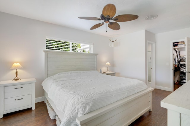 bedroom with dark wood-style flooring, a spacious closet, baseboards, a closet, and a ceiling fan