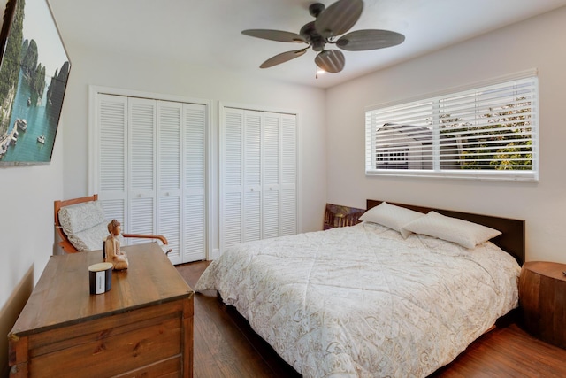 bedroom with multiple closets, dark wood-style floors, and a ceiling fan