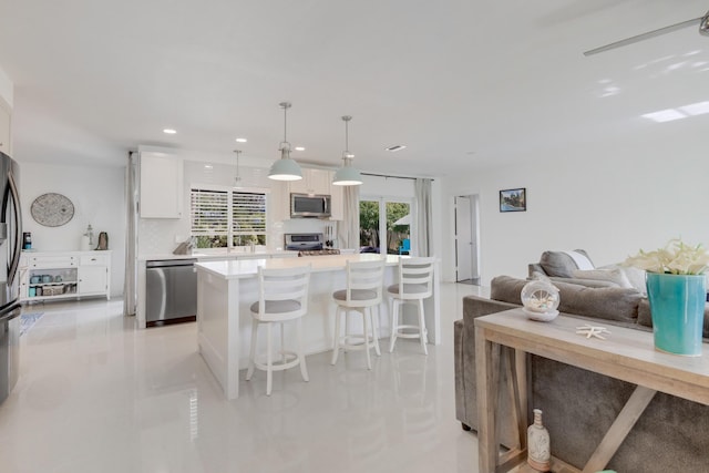 kitchen with stainless steel appliances, a breakfast bar area, white cabinets, light countertops, and recessed lighting