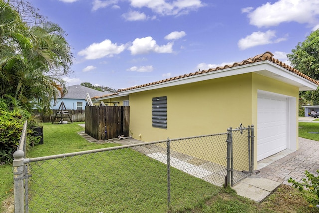 1401 Shore Dr, Lake Clarke Shores, FL 33406 - view of home's exterior featuring stucco siding, a tiled roof, a gate, and a detached garage