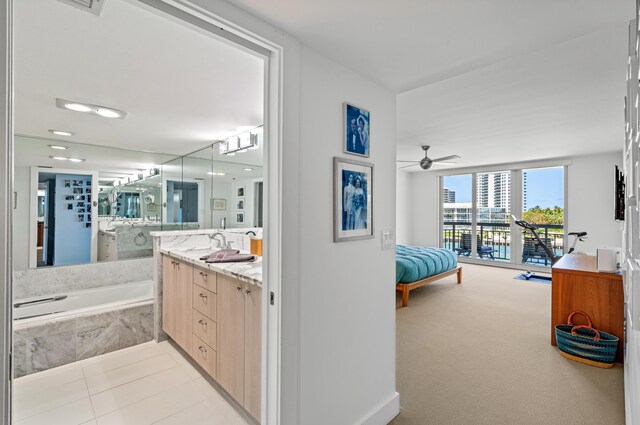 901 E Camino Real Unit 4C, Boca Raton, FL 33432 - full bathroom featuring ensuite bath, a tub with marble appearance, vanity, a ceiling fan, and tile patterned flooring