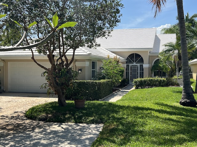 view of front of house with driveway, a front yard, an attached garage, stucco siding, and a tile roof