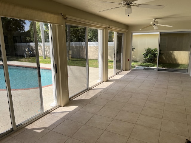 unfurnished sunroom featuring ceiling fan and plenty of natural light