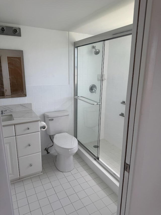 full bath with tile patterned flooring, a stall shower, tile walls, toilet, and vanity