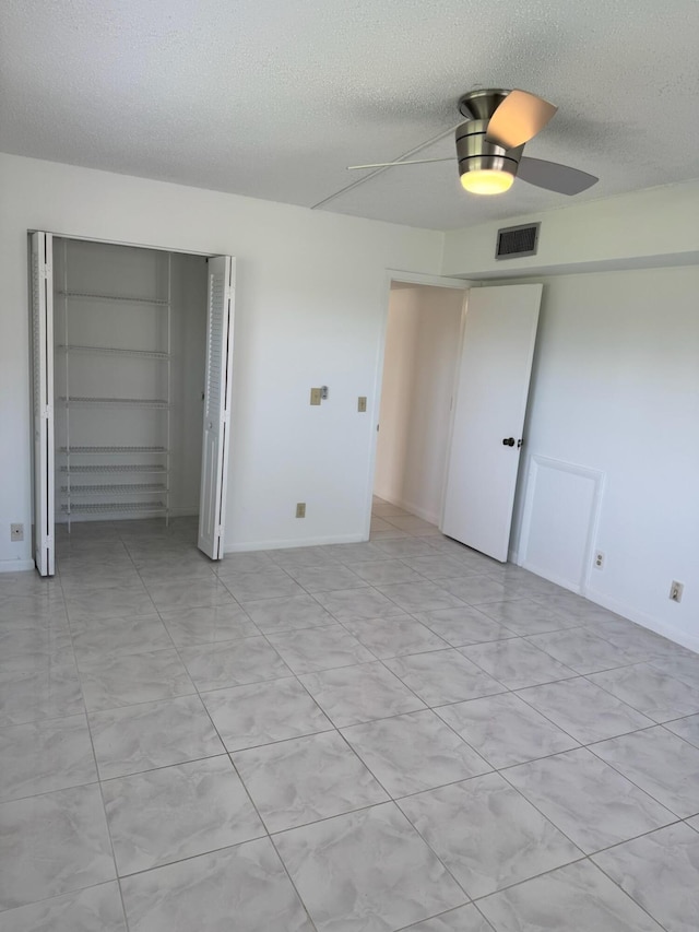 unfurnished bedroom featuring a textured ceiling, a closet, a ceiling fan, and baseboards