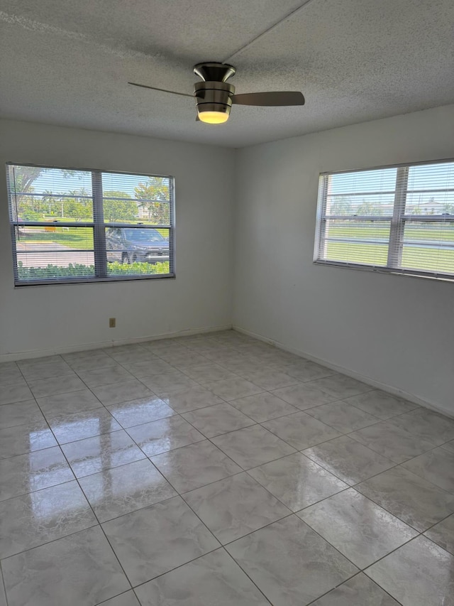 spare room with a ceiling fan, a textured ceiling, and baseboards
