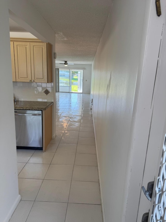kitchen featuring dishwasher, light brown cabinets, light tile patterned floors, a textured ceiling, and baseboards