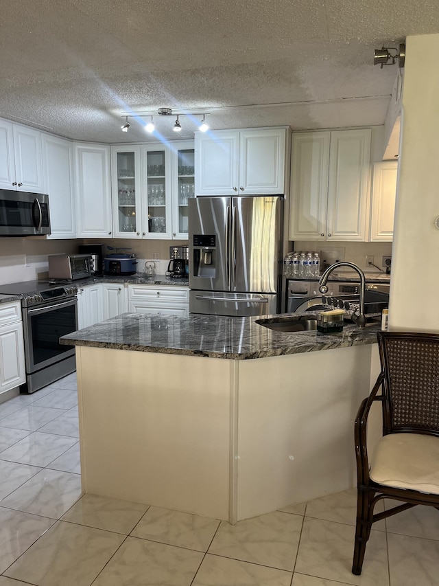 311 Pine Ridge Cir Unit B-1, Greenacres, FL 33463 - kitchen featuring stainless steel appliances, white cabinets, dark stone countertops, glass insert cabinets, and a peninsula