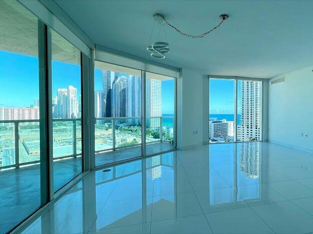 tiled spare room featuring floor to ceiling windows and a view of city