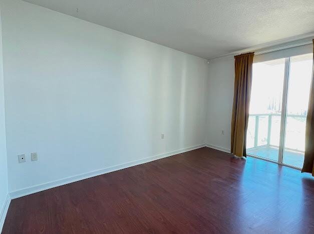 unfurnished room featuring wood finished floors, baseboards, and floor to ceiling windows